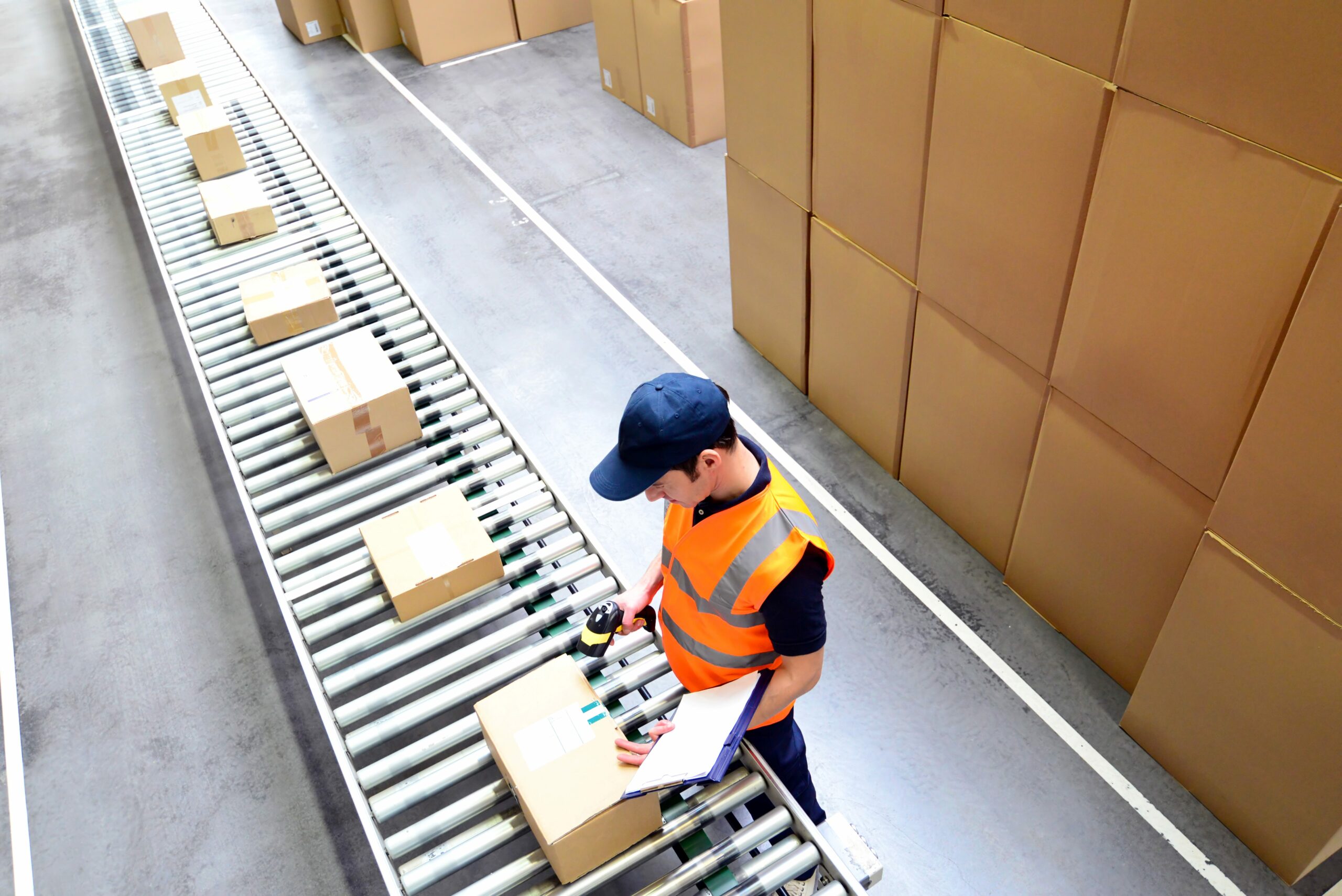 Man Scans Parcels For Mail Order Dispatch Assembly Line With Parcels