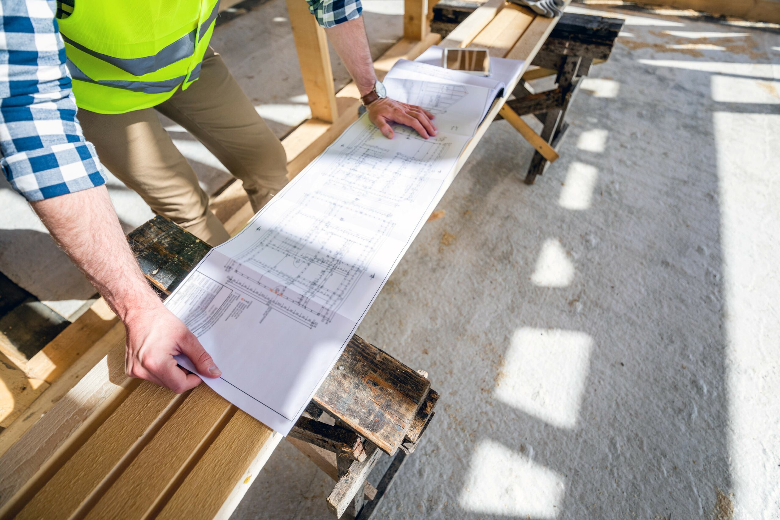 Architect Or Engineer On Construction Site Looking At Blueprints Of Building House