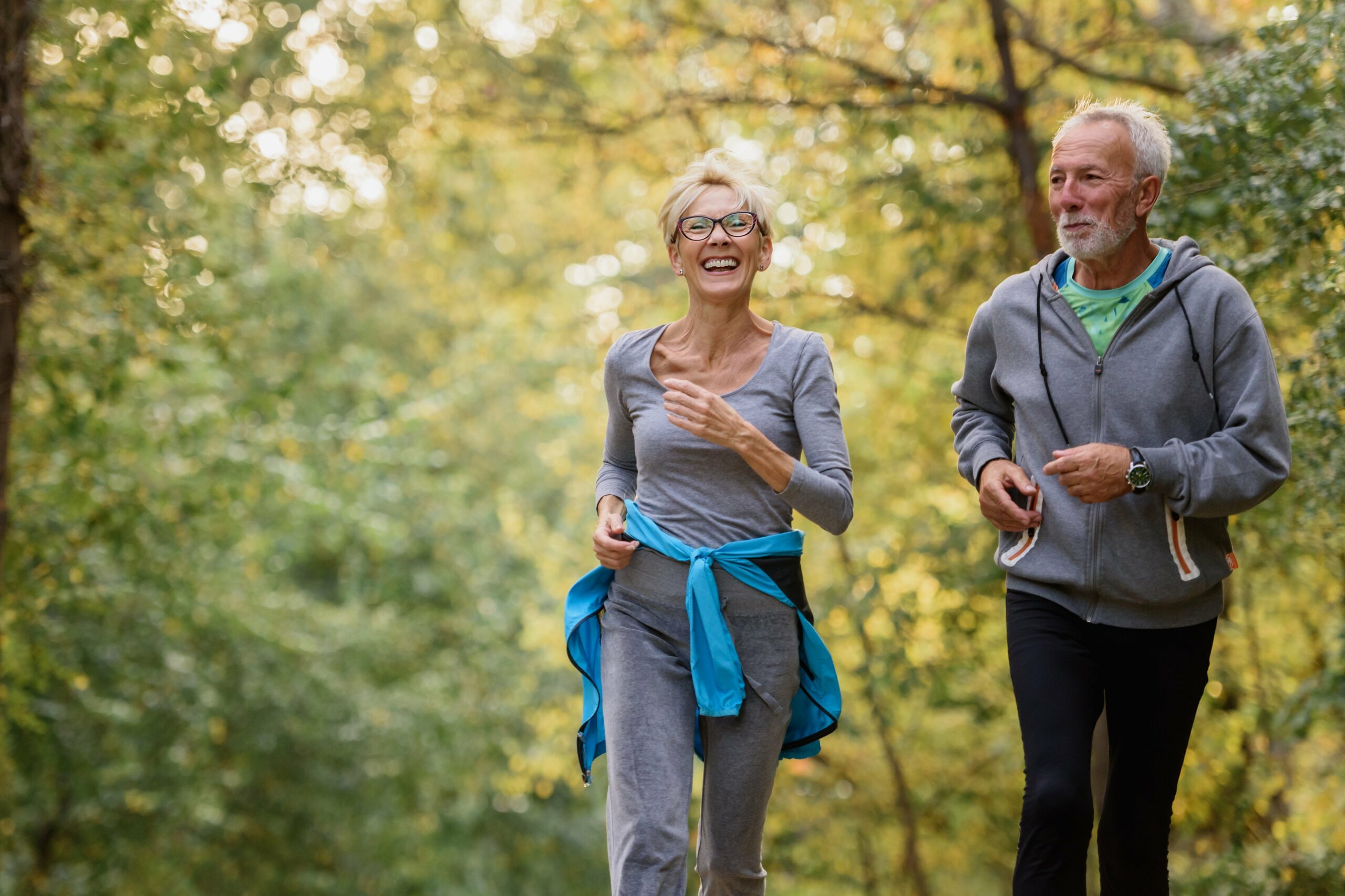 Cheerful Active Senior Couple Jogging In The Park.